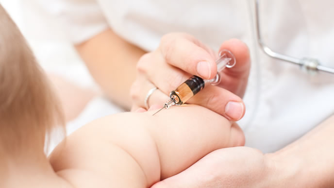 赤ちゃんの腕に予防接種を注射する看護師