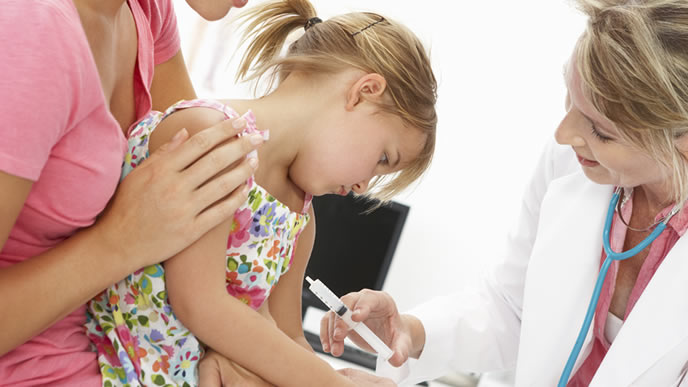 女の子の腕に予防接種を注射する女性医師