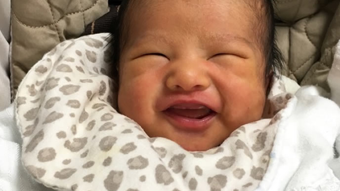 新生児微笑で大笑いする赤ちゃん