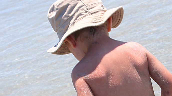 海で遊んで汚れた帽子をかぶる男の子