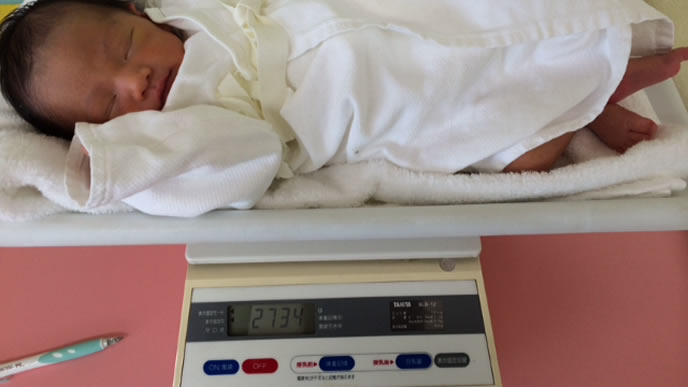 ミルク後の新生児の体重を計るママ