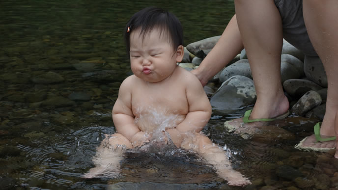 川の水が顔にかかる赤ちゃん