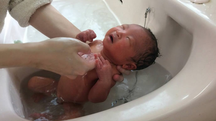 新生児の赤ちゃんを沐浴させるママ