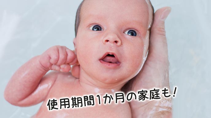 新生児が父親の手のひらに支えられて体を洗う