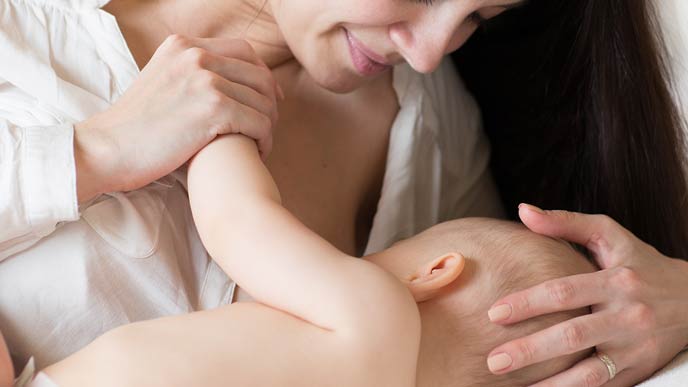 赤ちゃんの手を握り授乳する母親