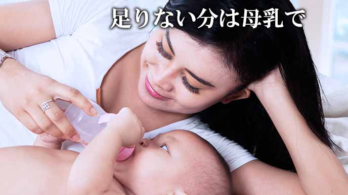 赤ちゃんに哺乳瓶でミルクを飲ませる母親