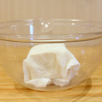 ボウルの中でキッチンペーパーに包まれ、水切りされる豆腐＠