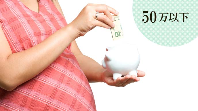貯金箱にお札を入れる妊婦