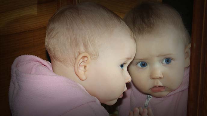 鏡を見て憂鬱そうな表情の赤ちゃん