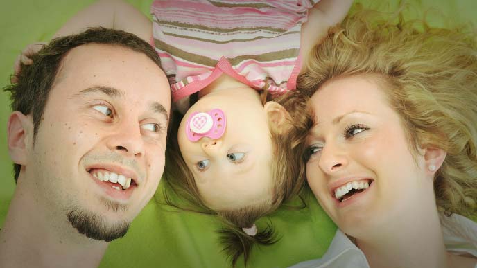 赤ちゃんを挟んで寝転がる女性と男性