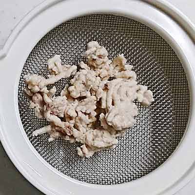 ラップに包まれた加熱済みかぼちゃと茶こしのうえにあげられた茹でた鶏ひき肉