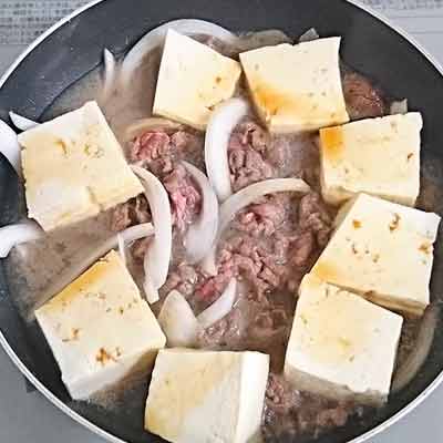 フライパンで炒め煮される牛肉と玉ねぎと豆腐