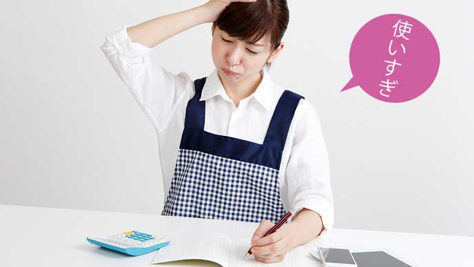 家計簿をつけながら嘆く女性
