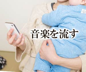 赤ちゃんを抱きながらスマホで選曲する女性