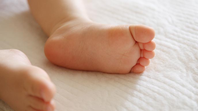 ソフトコットンの布地の上に赤ちゃんの足